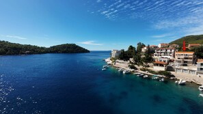 A coastal town with buildings along the waterfront, boats docked, and a clear blue sea. - Apartments Kuzma (Smokvica)