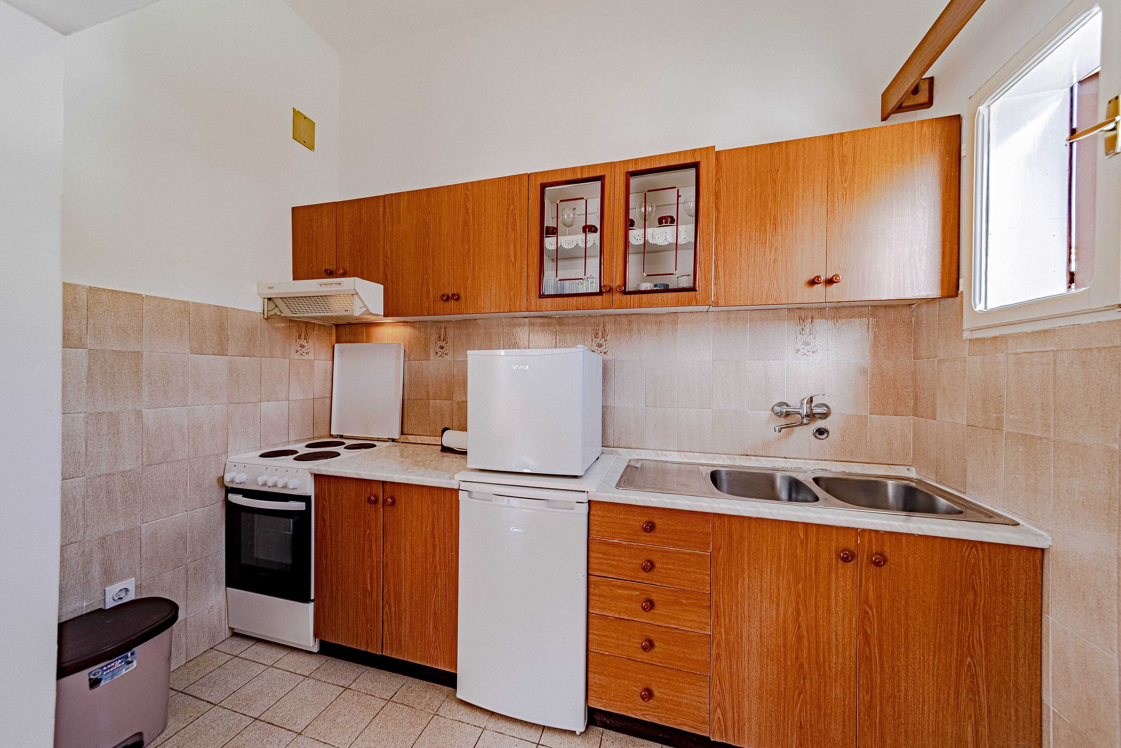 Una cocina con armarios de madera, estufa, refrigerador y lavaplatos.