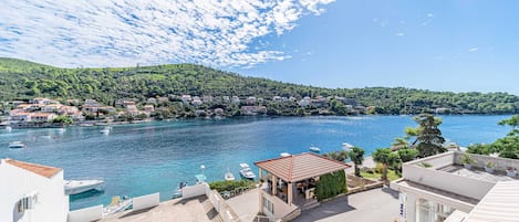 A coastal town with a marina, buildings with red roofs, and a clear blue sky.