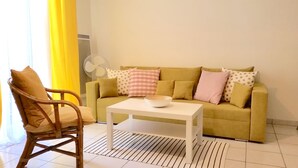 A living room with a yellow sofa, a white coffee table, and a wicker chair. - Lovely T2 with pool-near city and transport (CARCASSONNE)