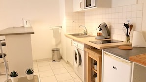 A compact kitchen with a washing machine, a sink, a microwave, and a small refrigerator. - Lovely T2 with pool-near city and transport (CARCASSONNE)