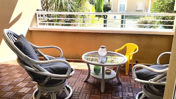 A balcony with wicker chairs, a small table, and a yellow chair. - Lovely T2 with pool-near city and transport (CARCASSONNE)