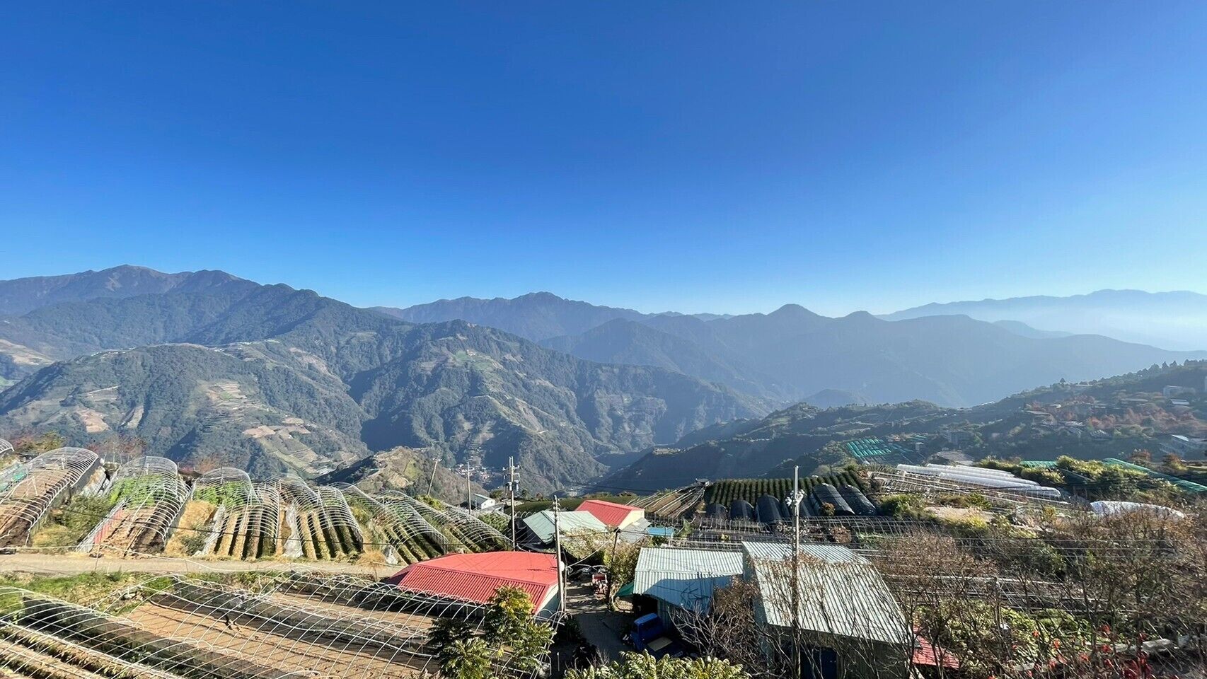 Un paysage montagneux avec des champs en terrasses et des bâtiments aux toits rouges.