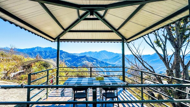 Un espacio de estar al aire libre cubierto, con una mesa y sillas, con vistas a un paisaje montañoso.