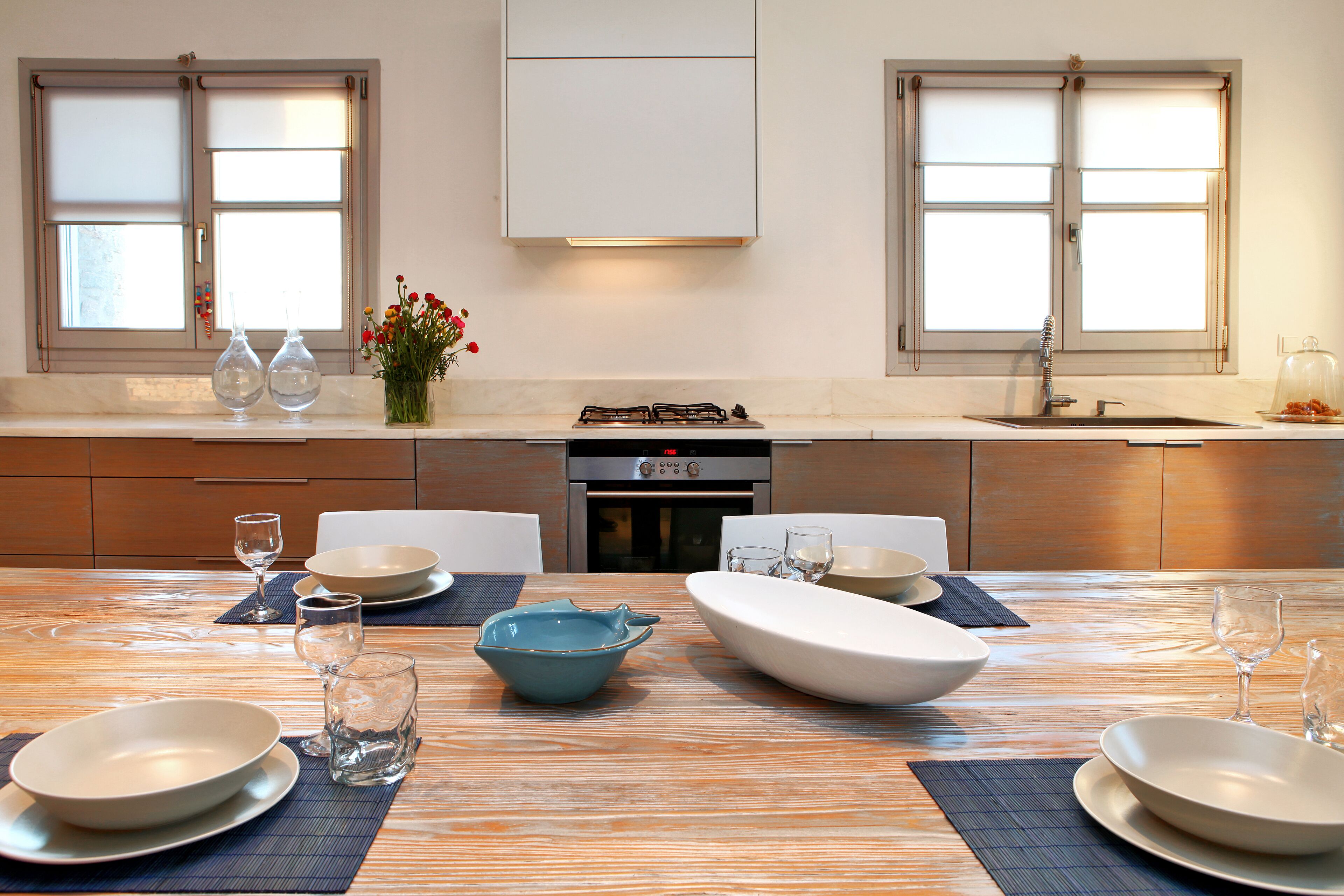 A modern kitchen with a dining table set for four, including plates, bowls, and glasses.