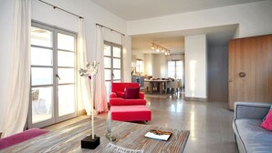 En moderne stue med en rød lænestol, en grå sofa og et spisebord i baggrunden.