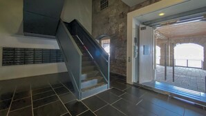 Un escalier menant à l’étage supérieur, un mur en pierre et une porte d’entrée en verre.