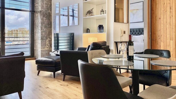 Un salon moderne doté d’une grande fenêtre, d’une cheminée et d’un coin repas avec des tables rondes.