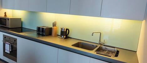 A modern kitchen with a microwave, toaster, kettle, and sink.