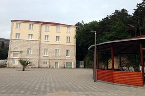 Un edificio a più piani con tetto in tegole, un cortile lastricato e un'area salotto all'aperto coperta.