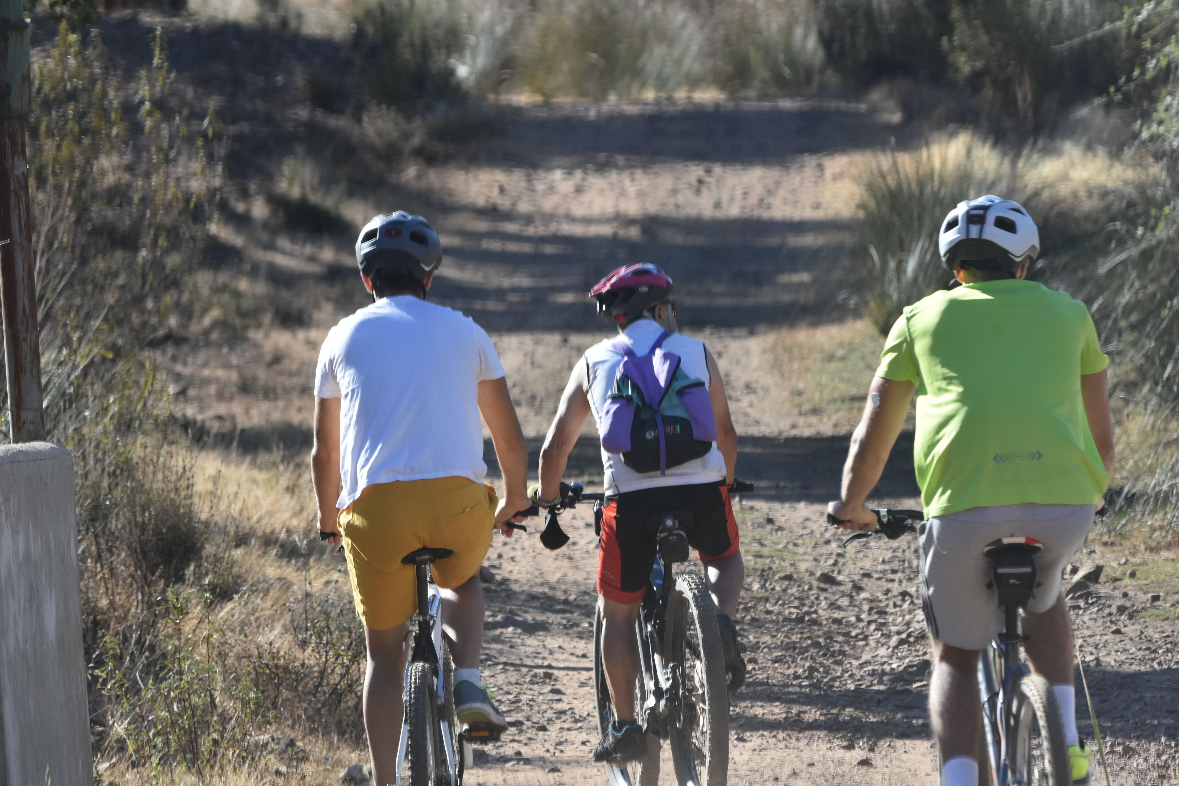 Tres personas andando en bicicleta por un sendero de tierra.