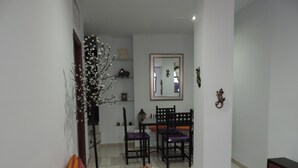 Una sala de estar con un sofá, una mesa de comedor con sillas y un espejo en la pared.