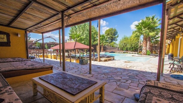 An outdoor seating area with stone flooring, a wooden table, and lounge chairs. - Relax and Recharge - only 34km from Barcelona! (Rubí)