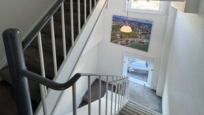 A staircase with a handrail, carpeted steps, and a view of a cityscape through a window at the top. - City & Station Stays at Gulland House by Pureserviced (Plymouth)