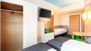 Habitación de hotel con dos camas individuales, un televisor montado en la pared, un armario de madera y una mesita con un taburete verde.
