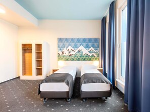 A hotel room with two beds, a painting of mountains, a wardrobe, and a window with curtains. - B&B Hotel Rosenheim (Rosenheim)
