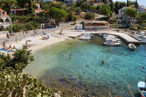 Une zone côtière caractérisée par des eaux limpides, une plage de sable et des bateaux amarrés dans une marina.