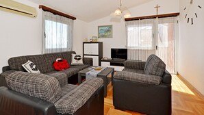 Olohuoneessa on sohvaryhmä, sohvapöytä, televisio ja seinällä oleva kello.