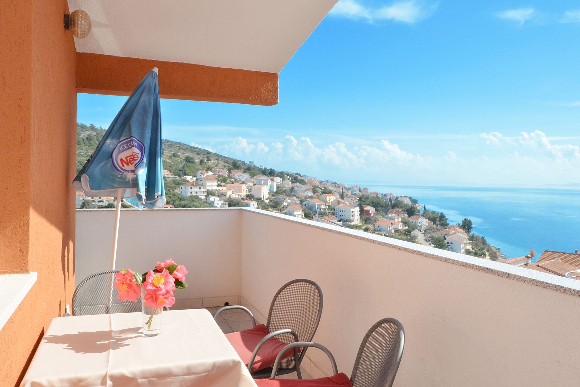 A balcony with a table, chairs, and a flag.