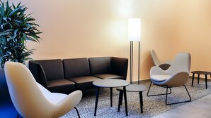 Un área de descanso moderna con un sofá, dos sillones, una mesita y una lámpara de pie.