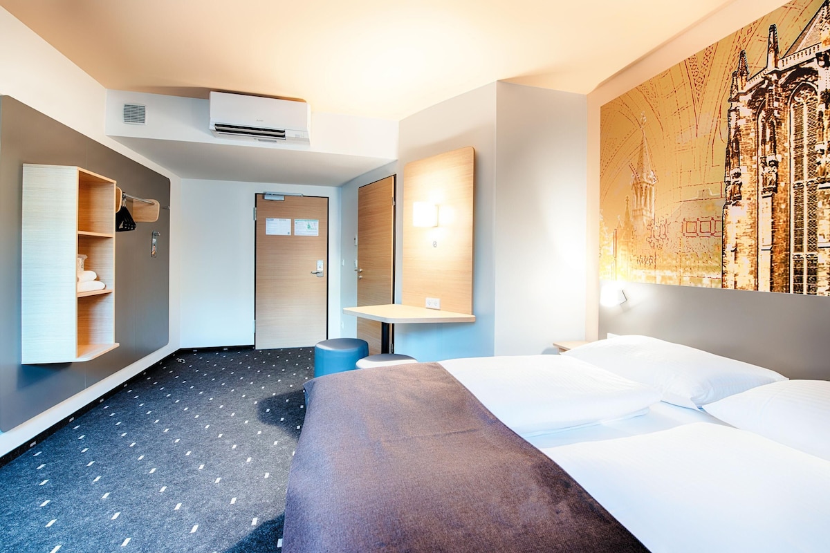 Een moderne hotelkamer met een groot bed, een bureau, een kledingkast en een wandairconditioner.