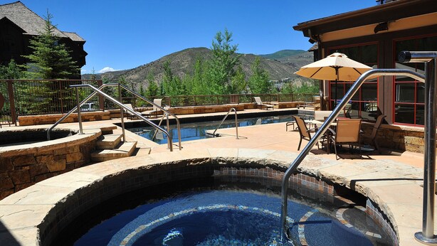 A hot tub with steps leading into it, surrounded by stone walls and a wooden deck. - Beaver Creek Landing A404 3 Bedroom Condo by RedAwning (Avon)