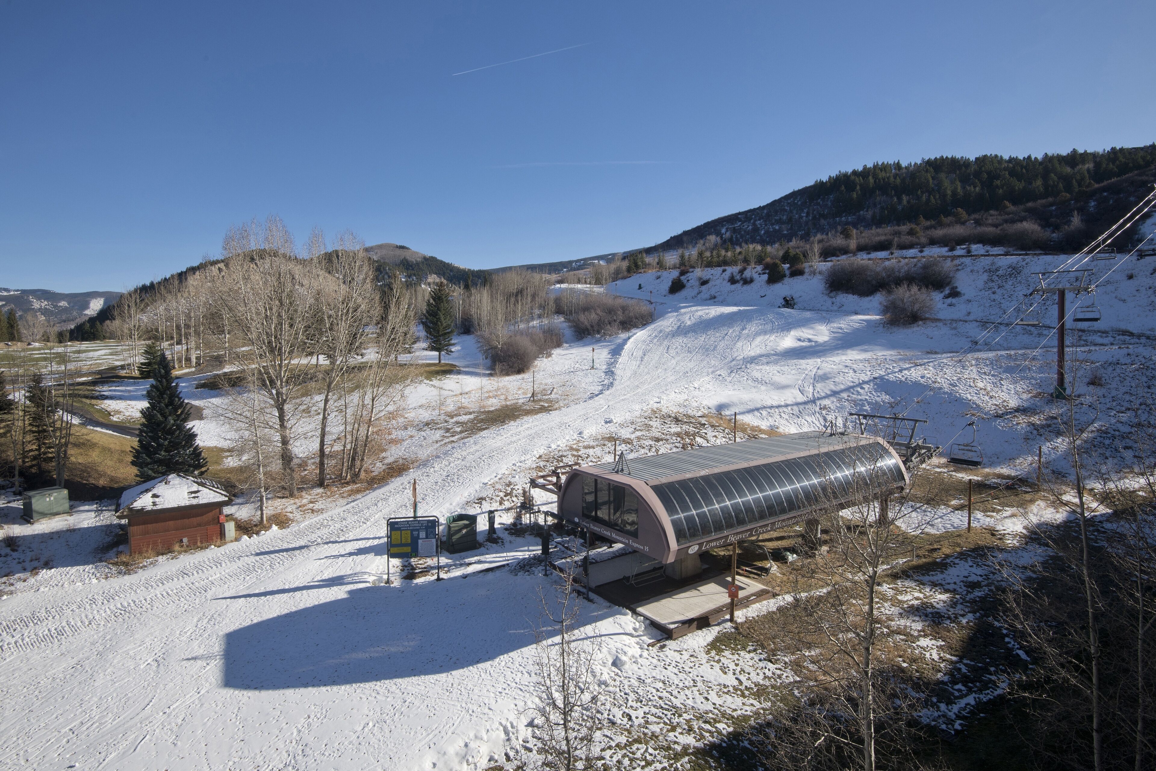 A solar-powered cabin with a metal roof, situated on a snowy slope with a clear sky.