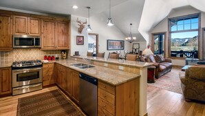 A spacious kitchen with wooden cabinets, a large island, stainless steel appliances, and a view of the outdoors. - Beaver Creek Landing A404 3 Bedroom Condo by RedAwning (Avon)