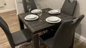 A dining table set with white plates and wine glasses, surrounded by black chairs. - Impeccable 2-bed Apartment in Birmingham (Birmingham)