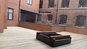 A courtyard with a wooden deck and a black planter. - Impeccable 2-bed Apartment in Birmingham (Birmingham)