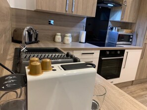 A compact kitchen with a built-in coffee maker, a toaster, and a microwave. - Impeccable 2-bed Apartment in Birmingham (Birmingham)