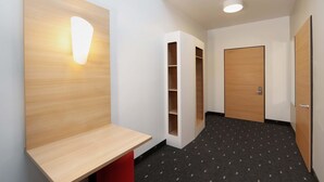 A modern hallway with a wooden bench, built-in shelving, and a door.