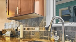 A kitchen with a granite countertop, stainless steel sink, and a stone backsplash. - Brekke's Basecamp 3 Bedroom Home by RedAwning (Park City)