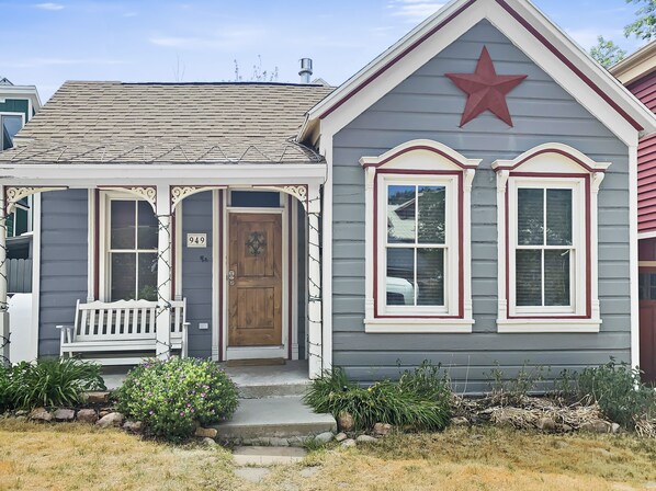 A two-story house with a front porch, a wooden door, and a red star on the gable. - Brekke's Basecamp 3 Bedroom Home by RedAwning (Park City)