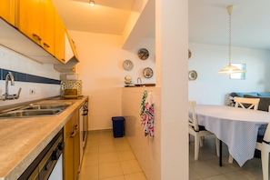 A kitchen with wooden cabinets, a sink, and a dining area with a table and chairs.