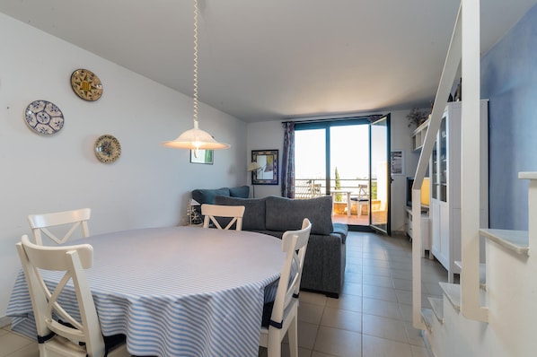 A dining area with a round table and chairs, a sofa, and a view of the outside.