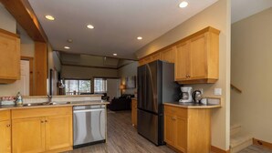A spacious kitchen with wooden cabinets, a stainless steel refrigerator, and a dishwasher.