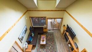 A compact living space with a lofted sleeping area, a sofa, a coffee table, a TV, and a fireplace.