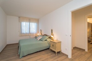 Une chambre à coucher avec un lit, des lampes de chevet, une table de chevet et une fenêtre avec des rideaux.