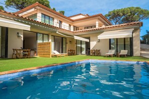 Une maison moderne dotée d’une piscine, d’un espace salon extérieur et d’un patio couvert.
