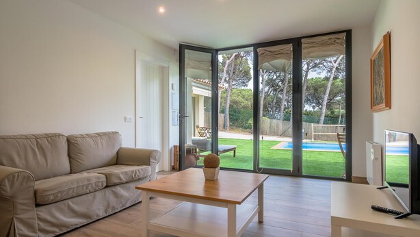 A modern living room with a beige sofa, a wooden coffee table, and a TV on a white stand.