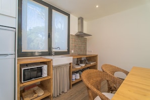 A compact kitchen with a microwave, sink, and wooden shelves.
