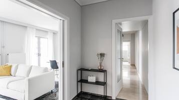 A modern hotel lobby with a white sofa, a black console table with a vase, and a marble floor.