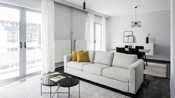 Ein modernes Wohnzimmer mit einer Couch, einem Couchtisch und einem Essbereich mit Tisch und Stühlen.