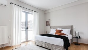 Ein modernes Schlafzimmer mit Bett, Nachttisch, Lampe und Blick ins Freie.
