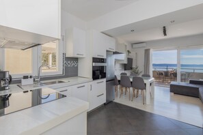 Eine moderne Küche mit Kochinsel, Essbereich mit Stühlen und Meerblick.