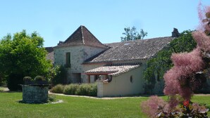A traditional stone building with a tiled roof, surrounded by a well-maintained lawn and flowering plants. - Luxury gite for adult couples, peaceful, open views, large swimming pool (Boisse)