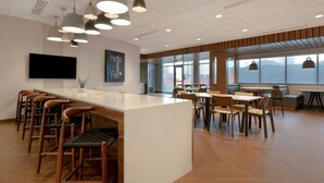 Un interior moderno con una barra central, diversas opciones de asientos y amplios ventanales que ofrecen vistas.