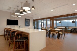 Un interior moderno con una barra central, diversas opciones de asientos y amplios ventanales que ofrecen vistas.