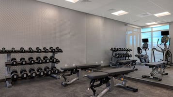 A gym with weightlifting equipment, benches, and treadmills.